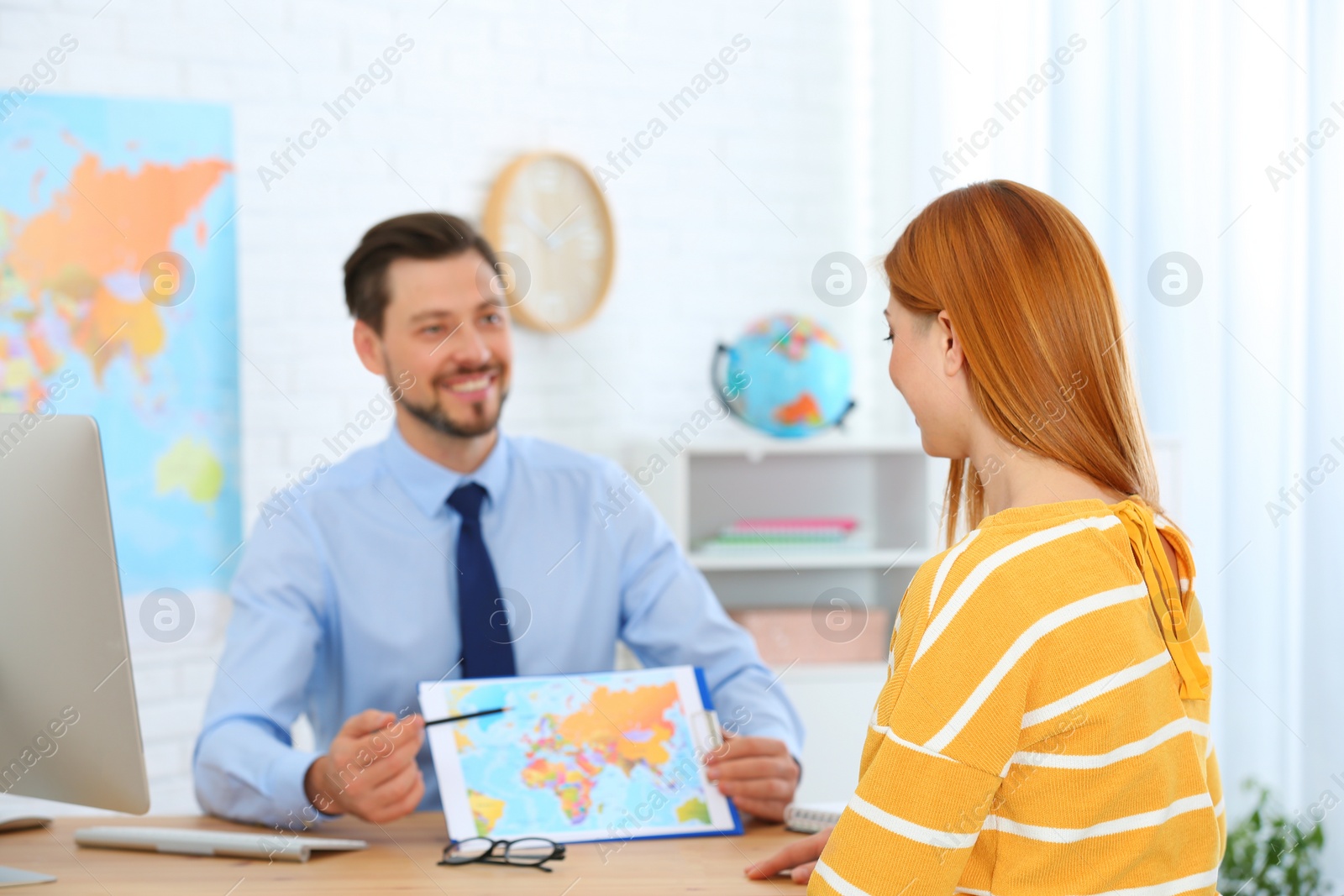 Photo of Male manager consulting client in travel agency