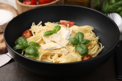 Photo of Delicious pasta with brie cheese, tomatoes and basil leaves on table, closeup