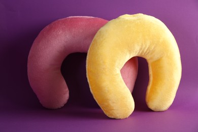 Photo of Pink and yellow travel pillows on violet background