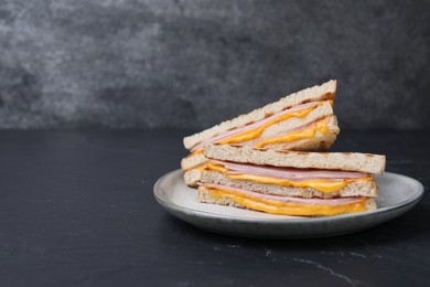 Photo of Delicious grilled sandwiches with ham and cheese on black table. Space for text
