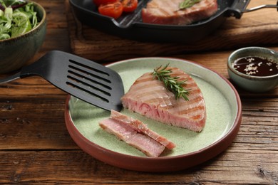 Photo of Delicious tuna steak with rosemary served on wooden table