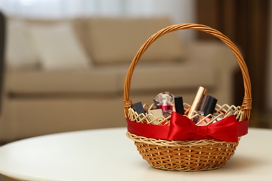 Photo of Wicker basket full of gifts on white table in living room. Space for text