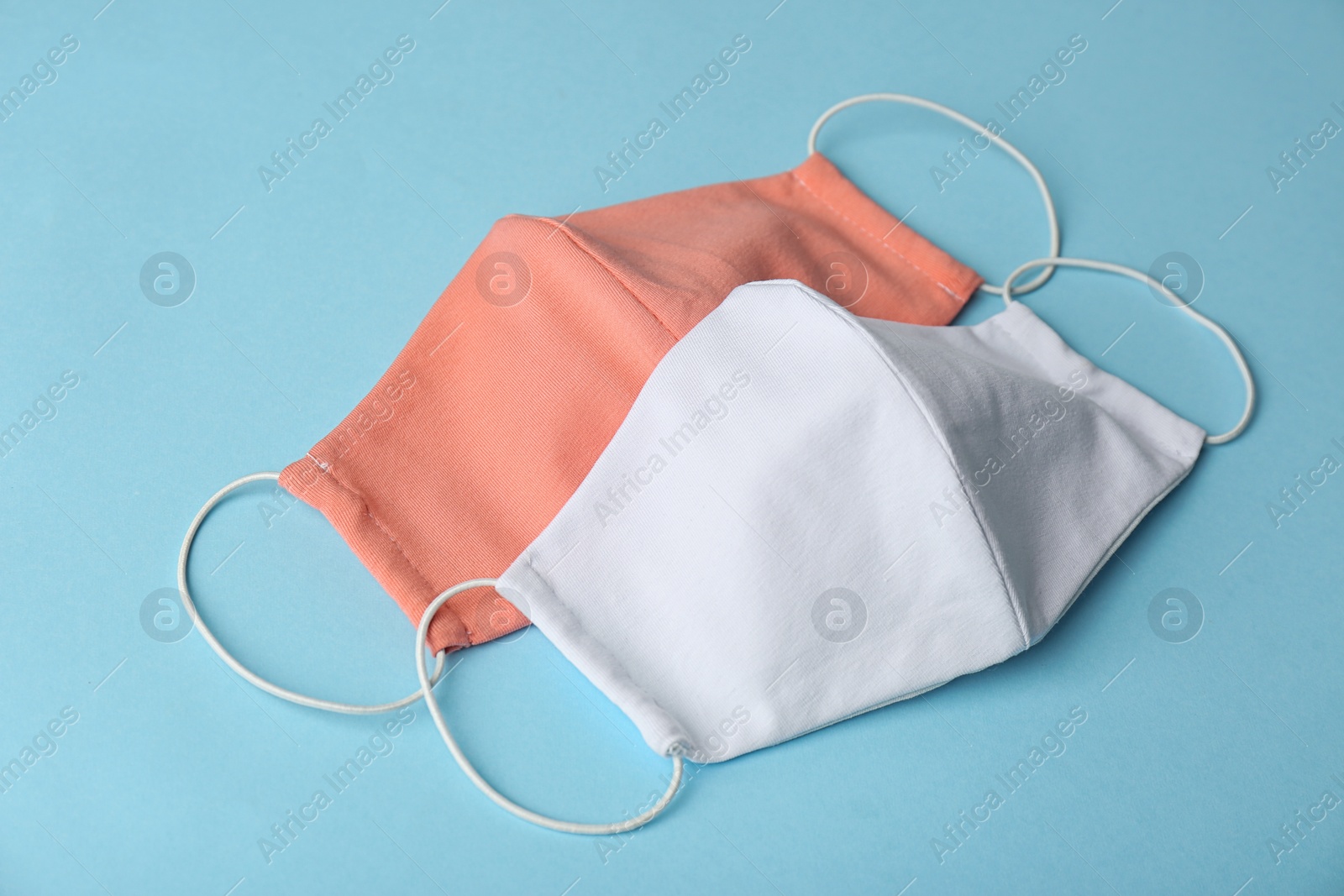 Photo of Homemade protective face masks on light blue background