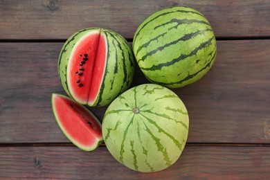 Photo of Different delicious ripe watermelons on wooden table, flat lay