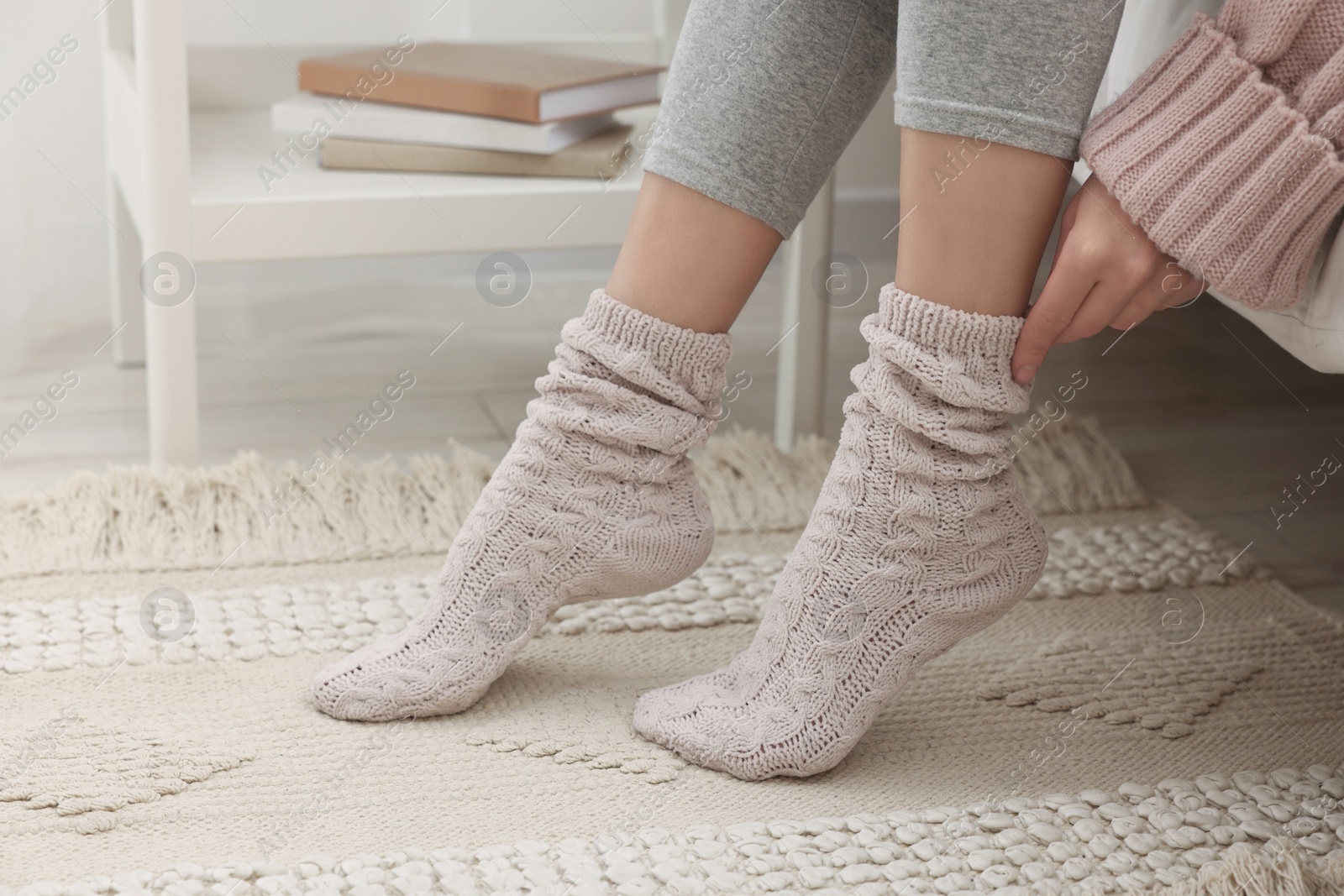 Photo of Woman wearing warm knitted socks at home, closeup