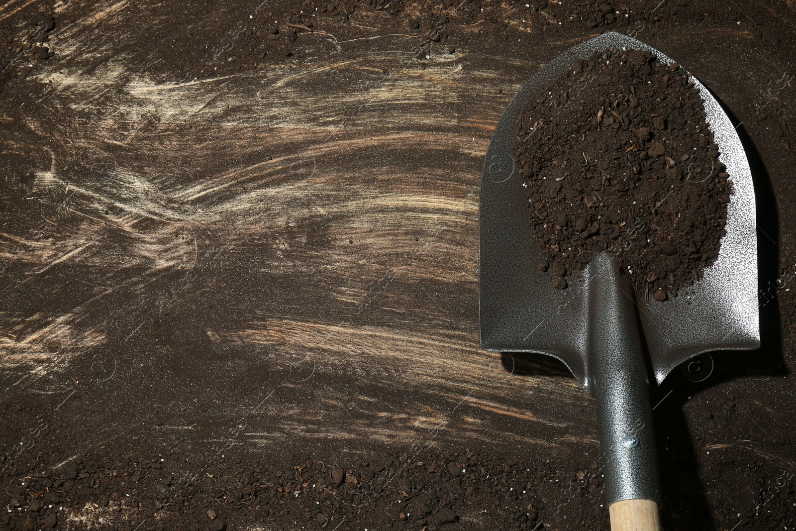 Metal shovel with fertile soil on dirty wooden surface, top view. Space for text Photo of Metal shovel with fertile soil on dirty wooden surface, top view. Space for text