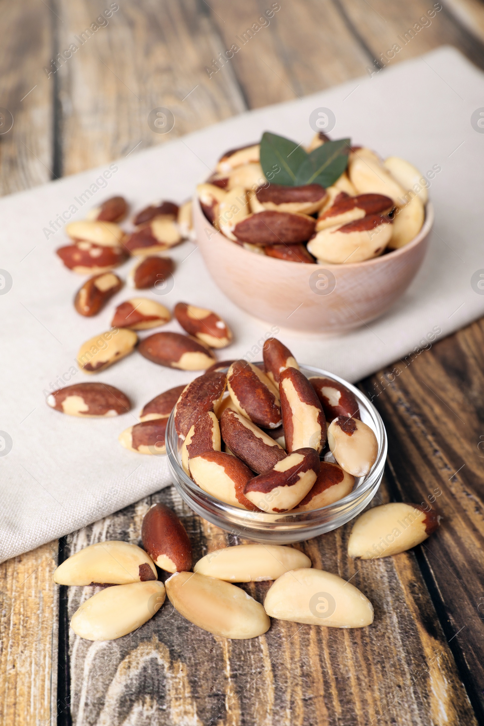 Photo of Bowls with delicious Brazil nuts on wooden table