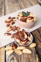 Photo of Bowls with delicious Brazil nuts on wooden table