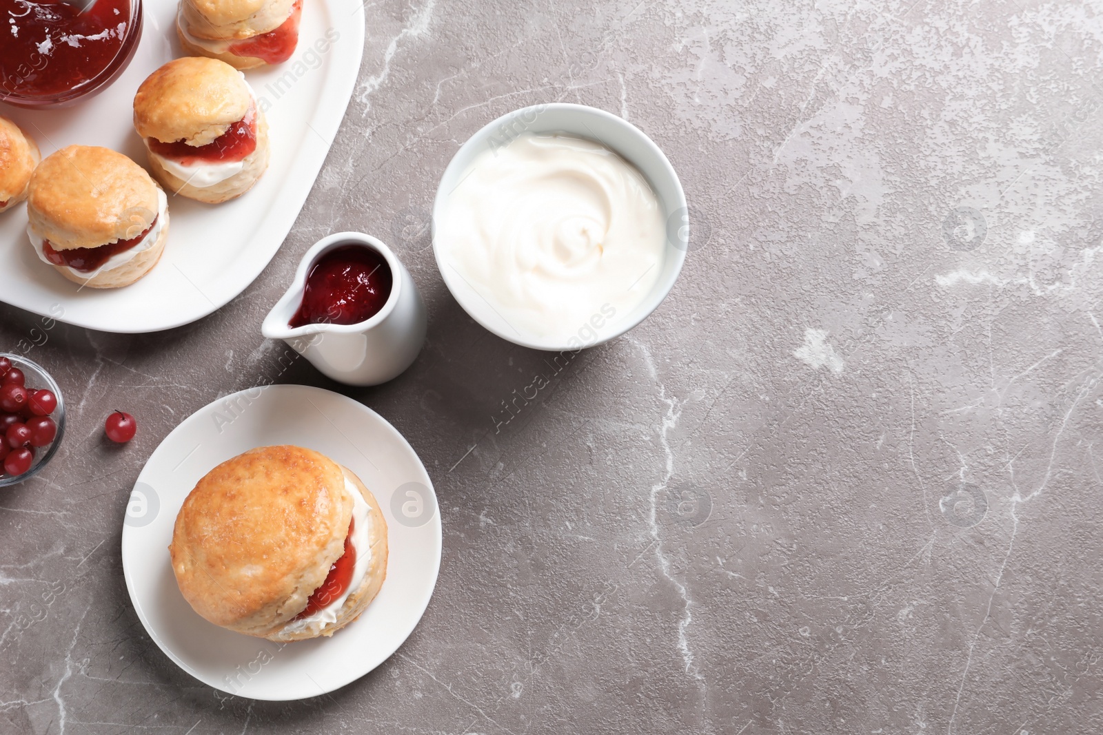 Photo of Tasty scones with clotted cream and jam on grey background, top view