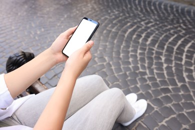 Photo of Woman with smartphone sitting on bench outdoors, closeup