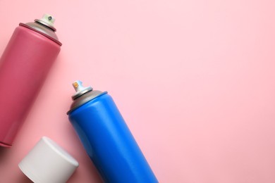 Photo of Cans of different graffiti spray paints on pink background, flat lay. Space for text
