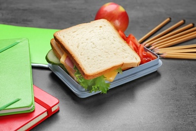 Photo of Lunch box with tasty sandwich and stationery on table