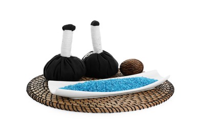 Photo of Wicker mat with blue sea salt and herbal bags isolated on white