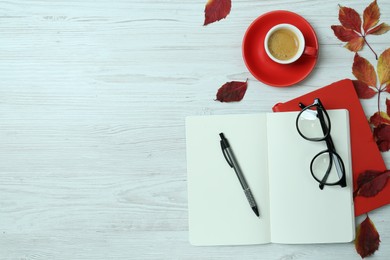 Flat lay composition with open notebook and autumn leaves on white wooden table, space for text