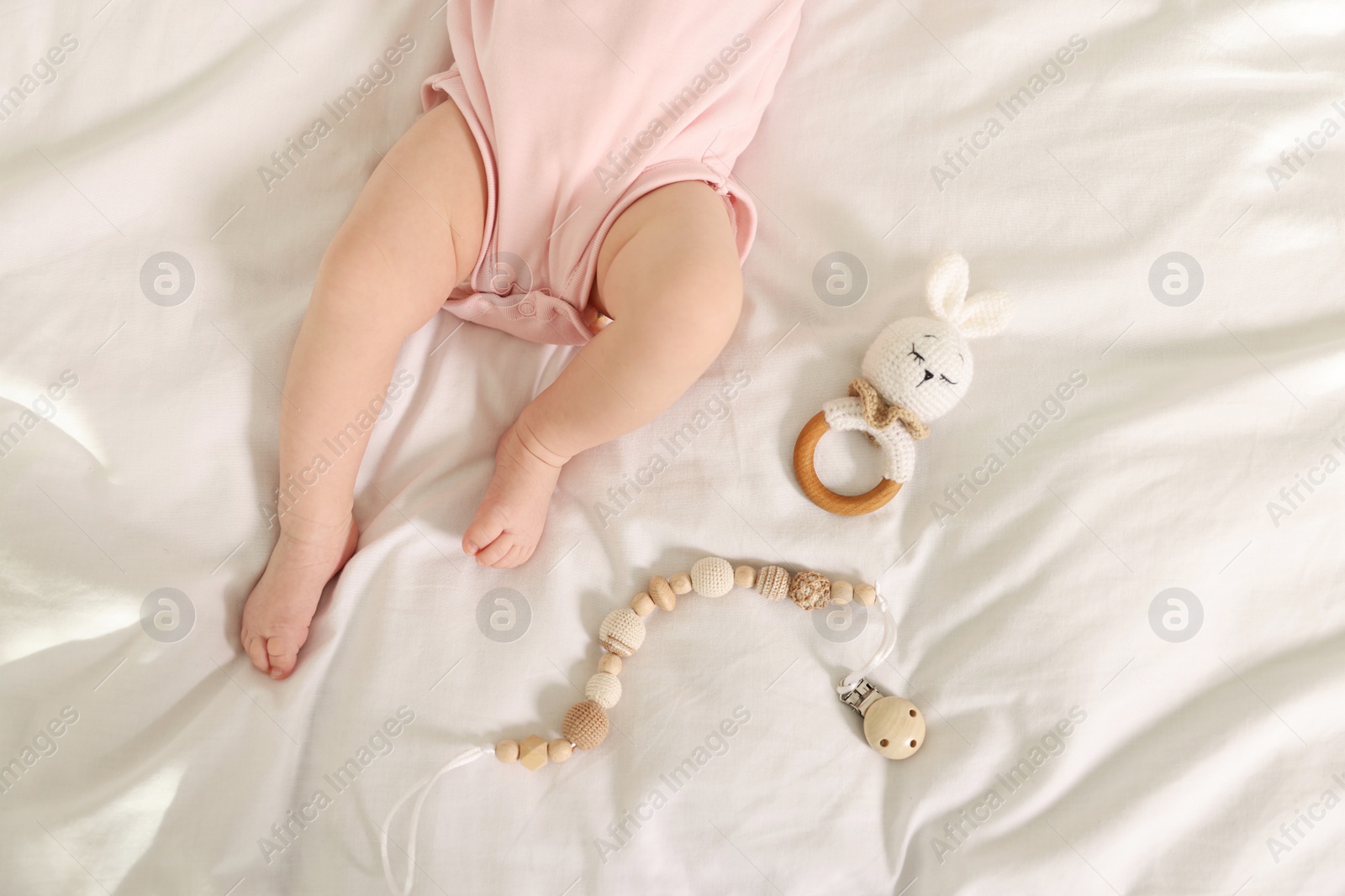 Photo of Cute baby with rattle and teether toys on sheets, top view