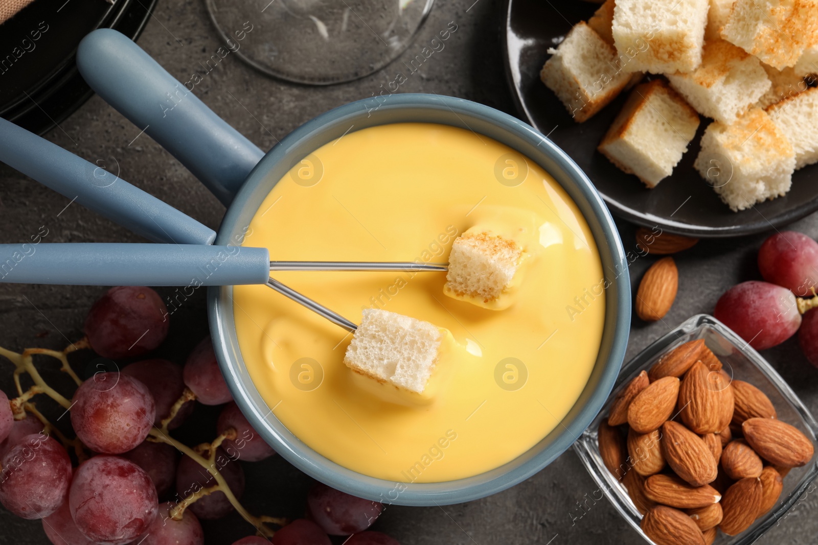 Photo of Flat lay composition with pot of tasty cheese fondue on grey table