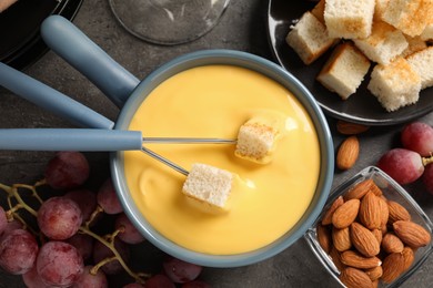 Photo of Flat lay composition with pot of tasty cheese fondue on grey table