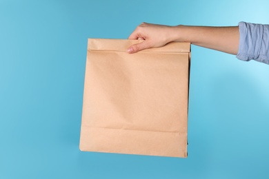 Woman holding paper bag on color background. Mockup for design