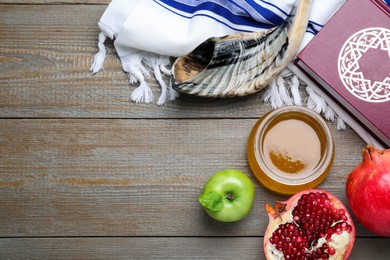 Photo of Honey, pomegranate, apples, shofar and Torah on wooden table, flat lay with space for text. Rosh Hashana holiday