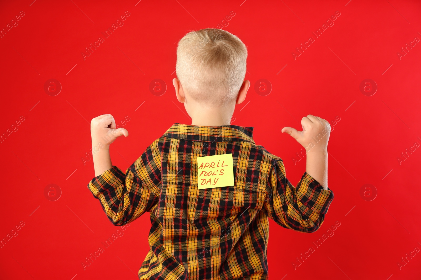 Photo of Little boy with APRIL FOOL'S DAY sticker on back against red background