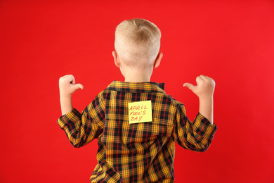 Photo of Little boy with APRIL FOOL'S DAY sticker on back against red background