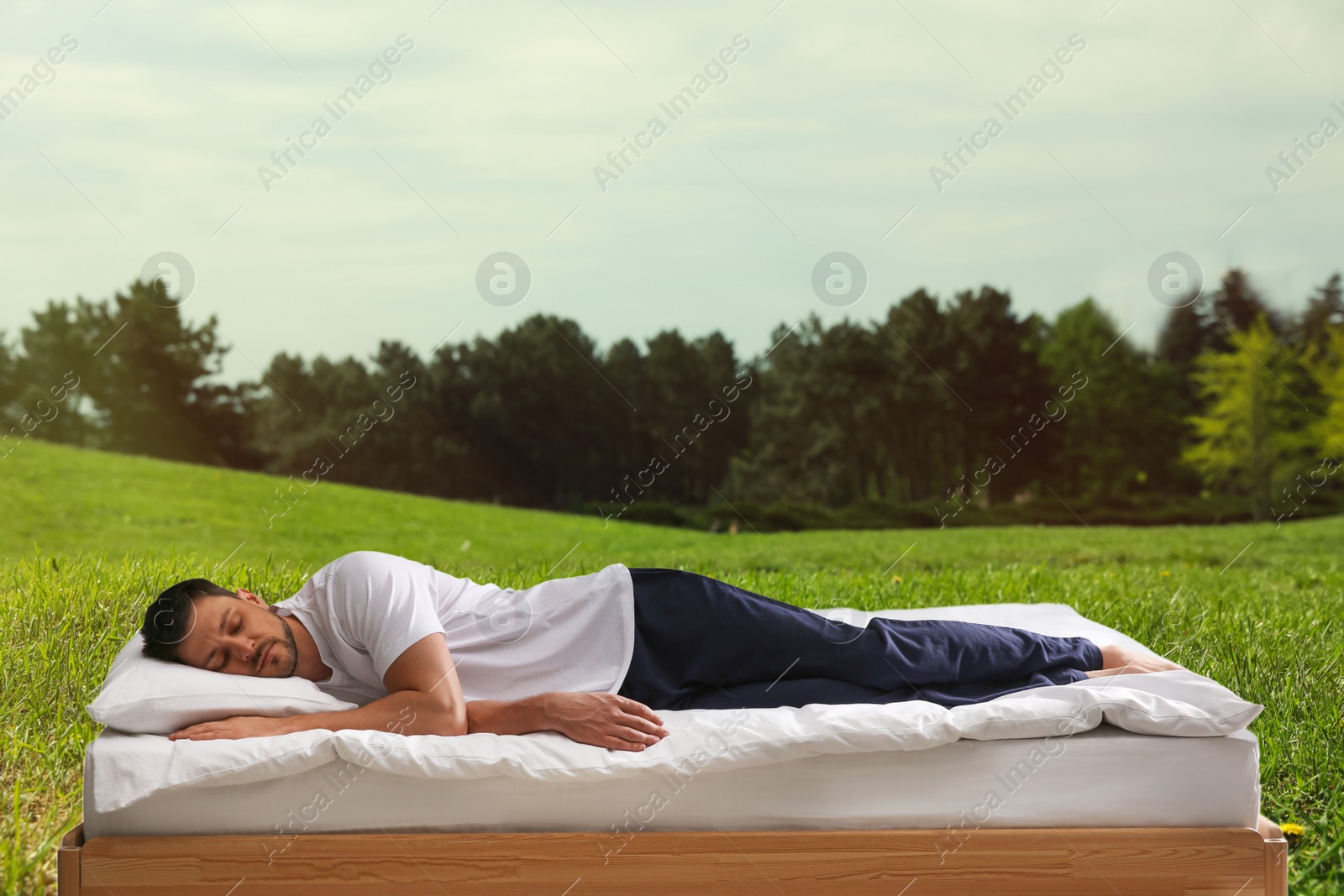 Image of Man sleeping on bed and beautiful view of green lawn on background. Sleep well - stay healthy