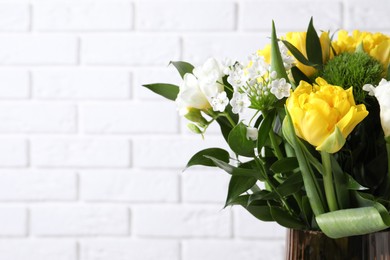 Photo of Beautiful bouquet with peony tulips near white brick wall, closeup. Space for text