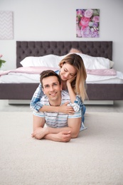 Lovely young couple lying on cozy carpet at home