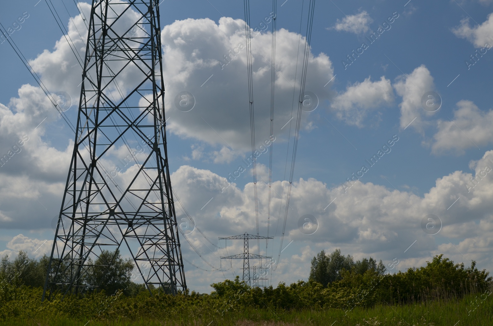 Photo of Modern high voltage towers in field on sunny day, space for text