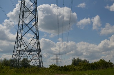 Modern high voltage towers in field on sunny day, space for text