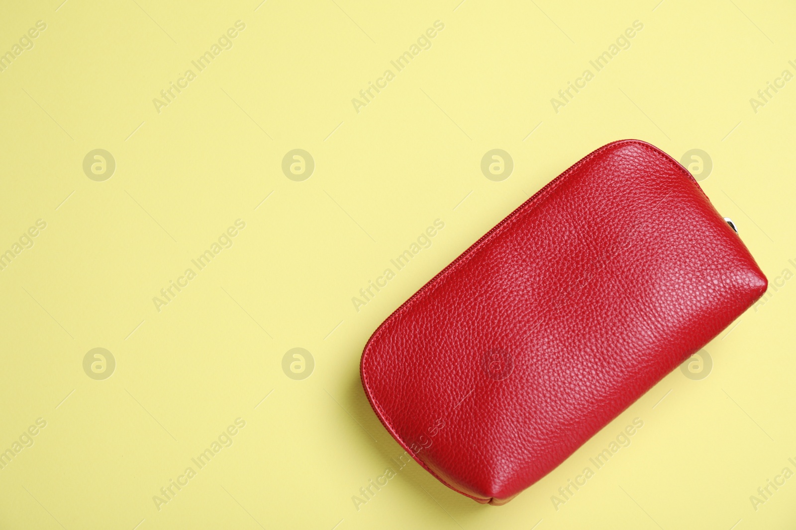 Photo of Red leather cosmetic bag on yellow background, top view. Space for text