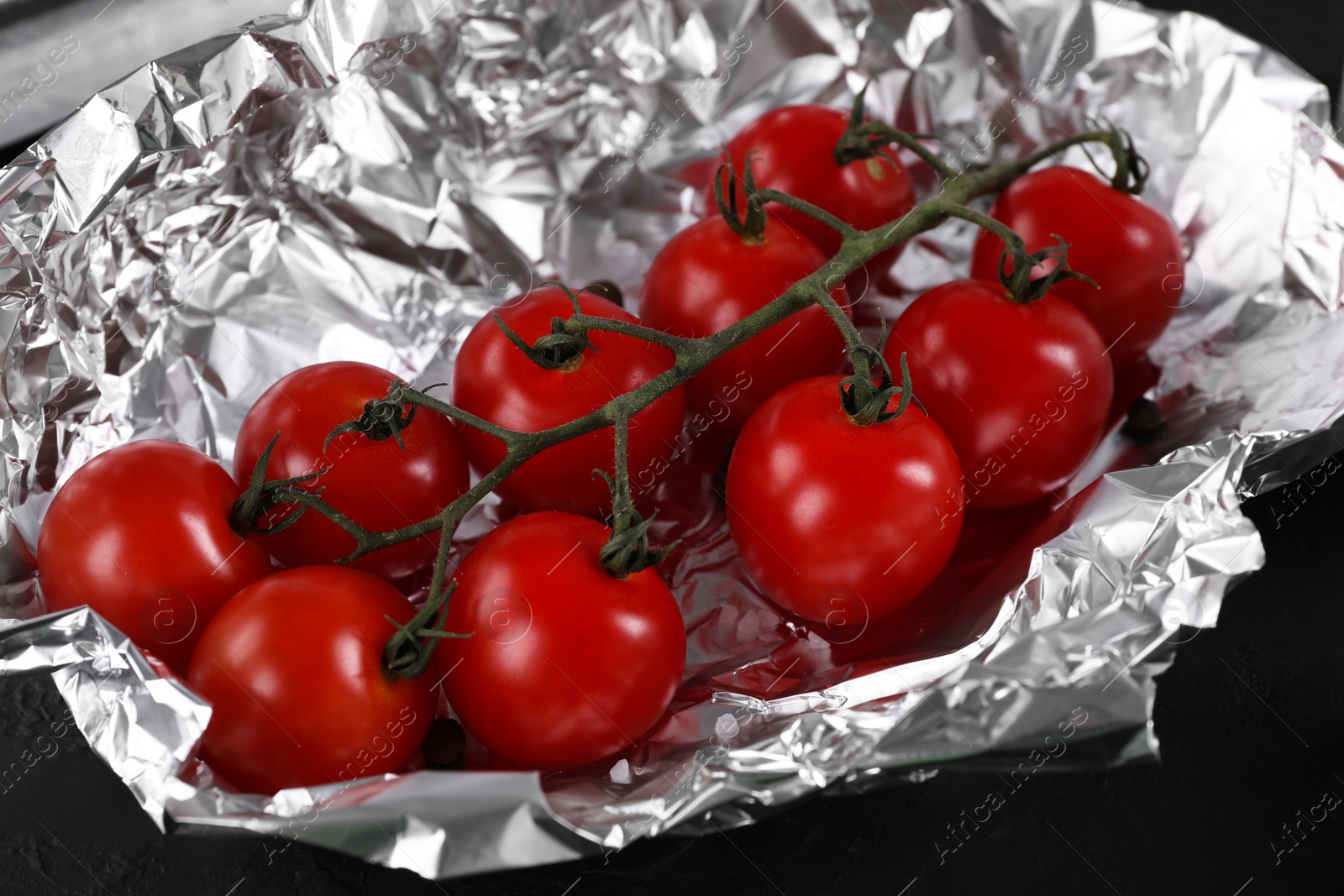 Photo of Tomatoes in aluminum foil on dark table, closeup