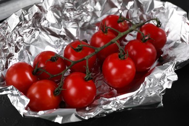 Tomatoes in aluminum foil on dark table, closeup