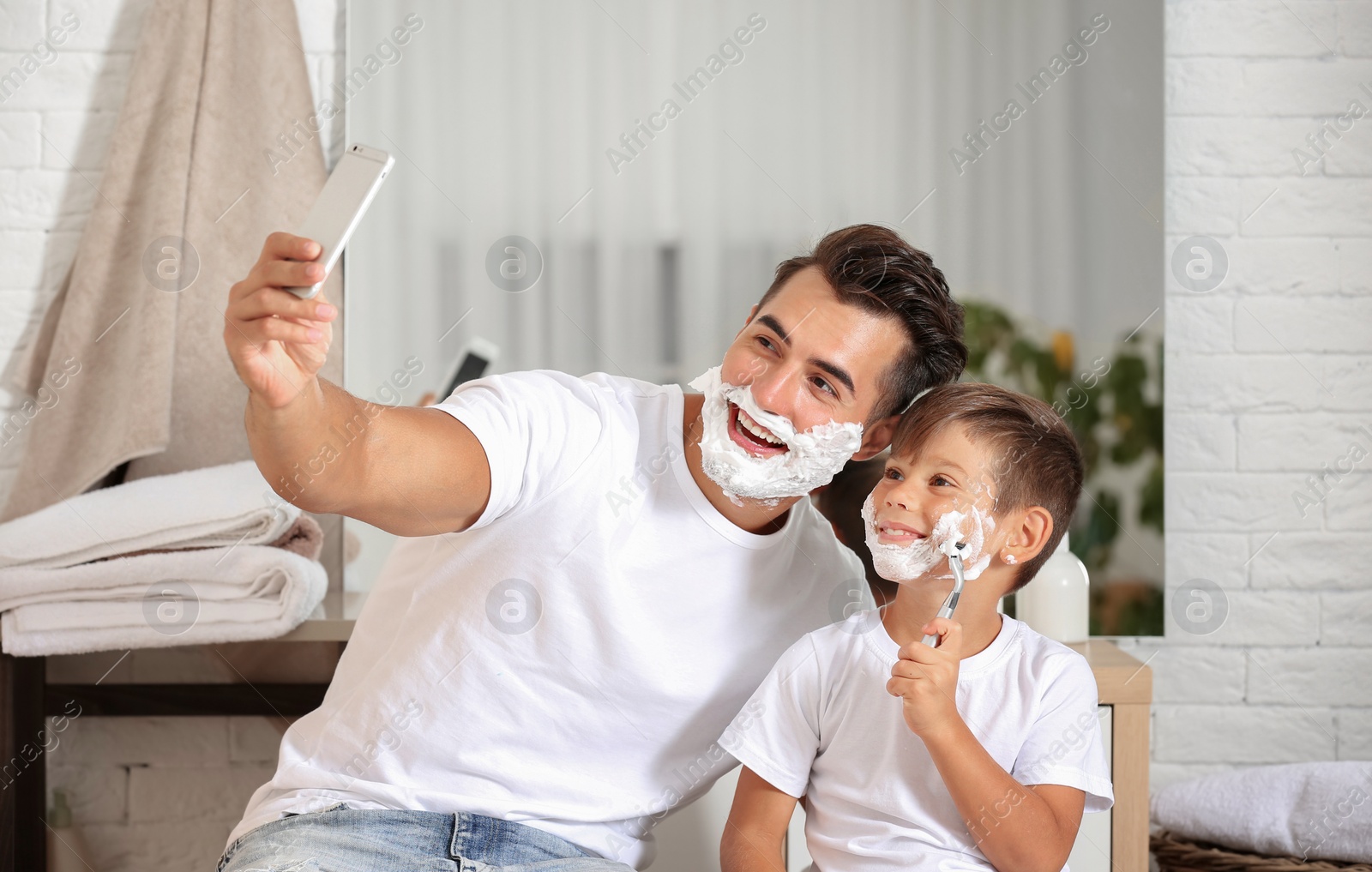 Photo of Father and son taking selfie while shaving in bathroom