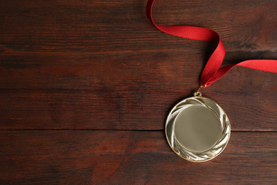 Gold medal on wooden background, top view. Space for design