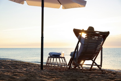 Photo of Man relaxing on deck chair at sandy beach. Summer vacation