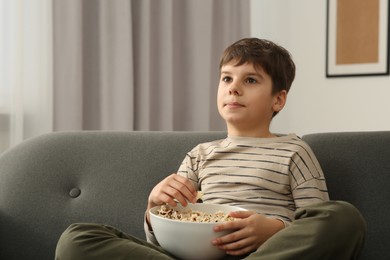 Little boy eating popcorn while watching TV at home
