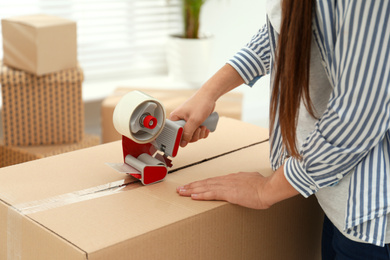 Photo of Woman packing cardboard box indoors, closeup. Moving day