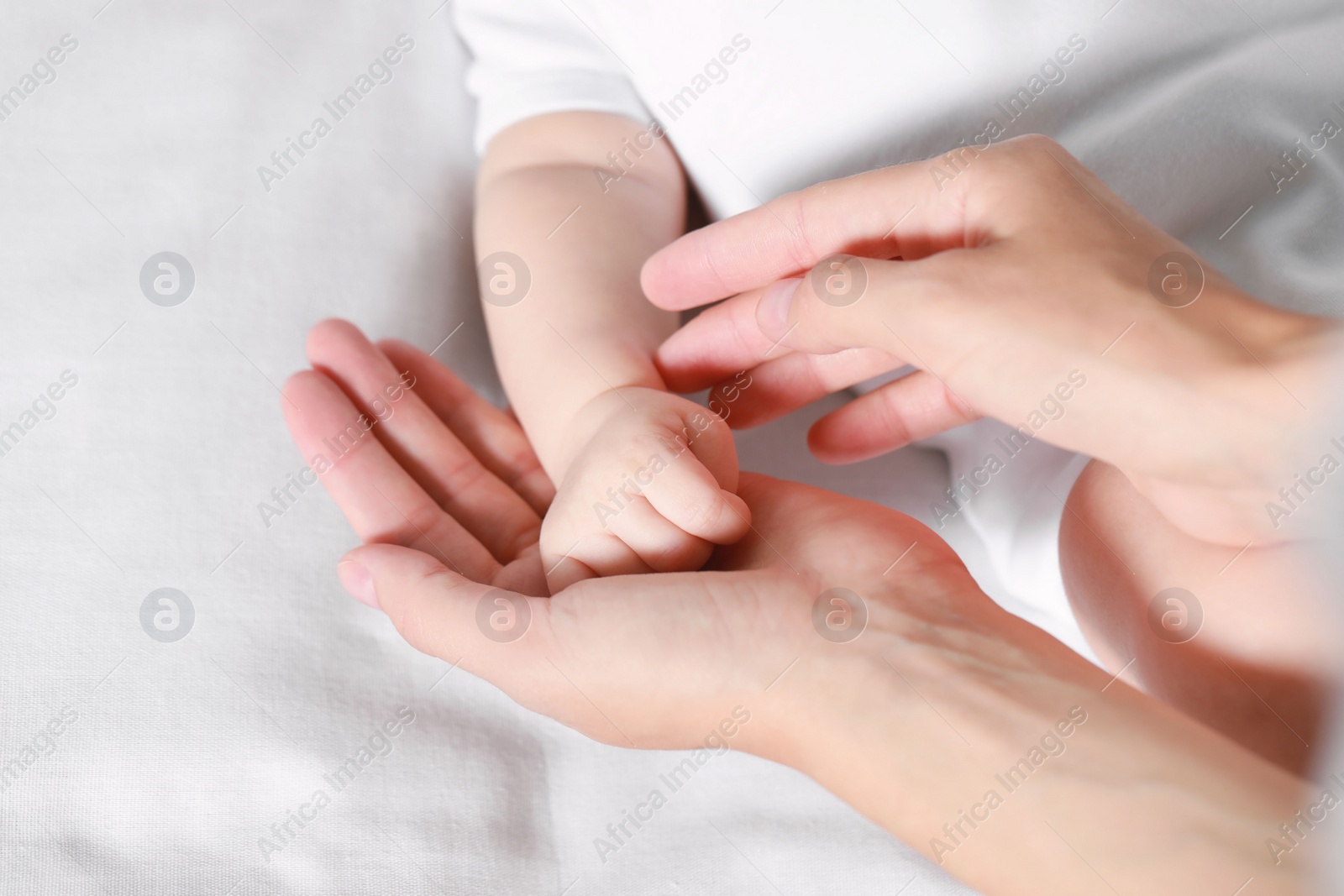Photo of Mother holding hand of her baby on bed, closeup