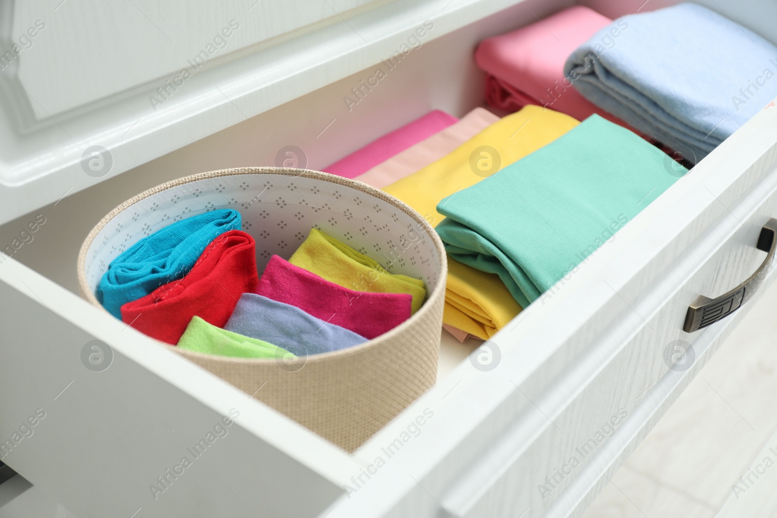 Photo of Chest of drawers with different folded clothes indoors, closeup