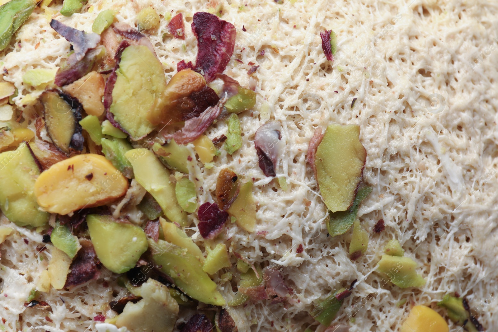 Photo of Tasty halva with pistachios as background, top view