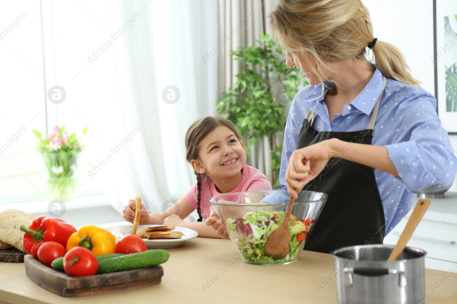 Photo of Young nanny with cute little girl cooking together in kitchen