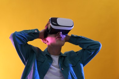 Young man with virtual reality headset on yellow background