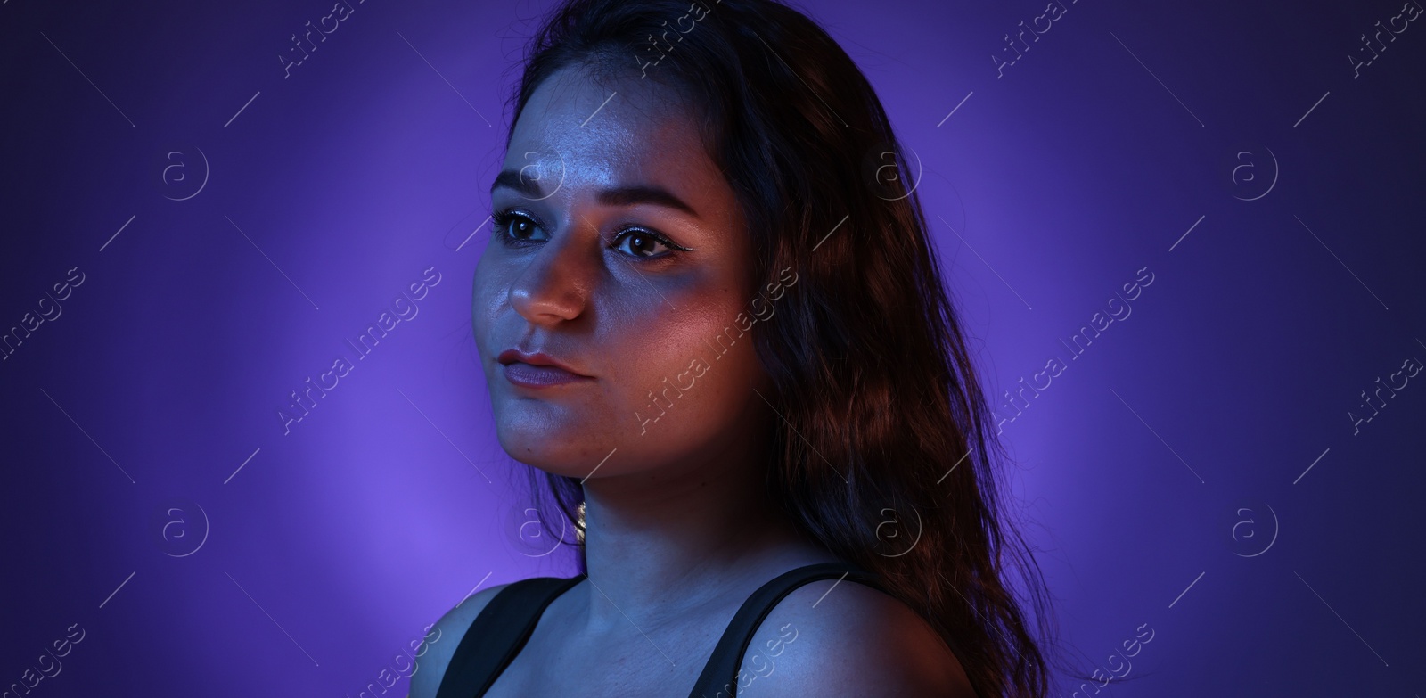 Photo of Portrait of beautiful young woman on color background with neon lights