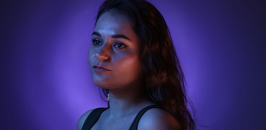 Photo of Portrait of beautiful young woman on color background with neon lights