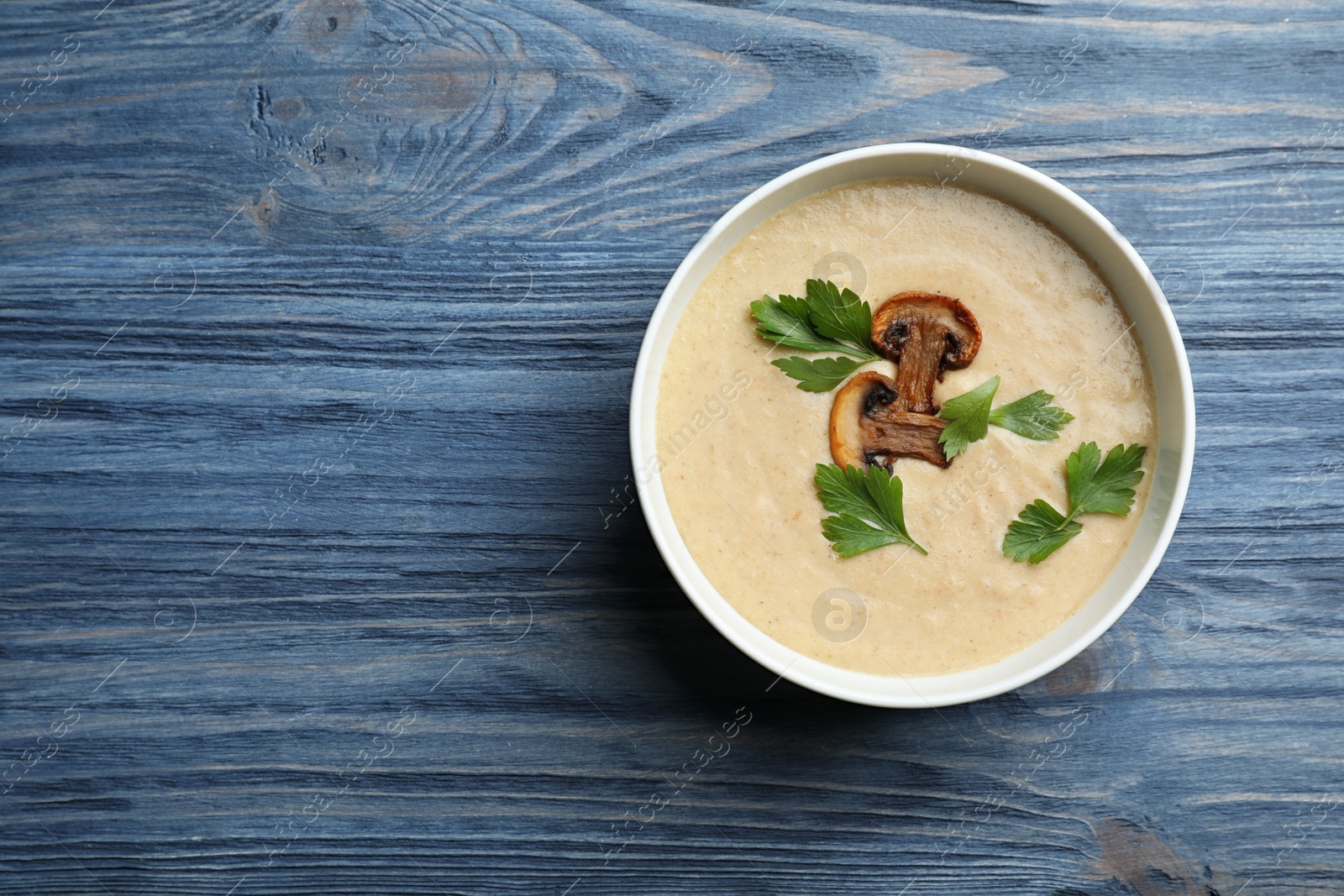 Photo of Bowl of fresh homemade mushroom soup on wooden background, top view with space for text