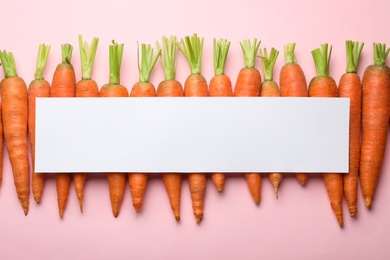 Flat lay composition with fresh carrots and blank card on color background. Space for text