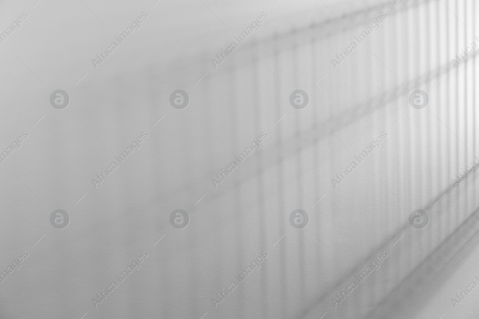 Photo of Light and shadows on white wall, space for text