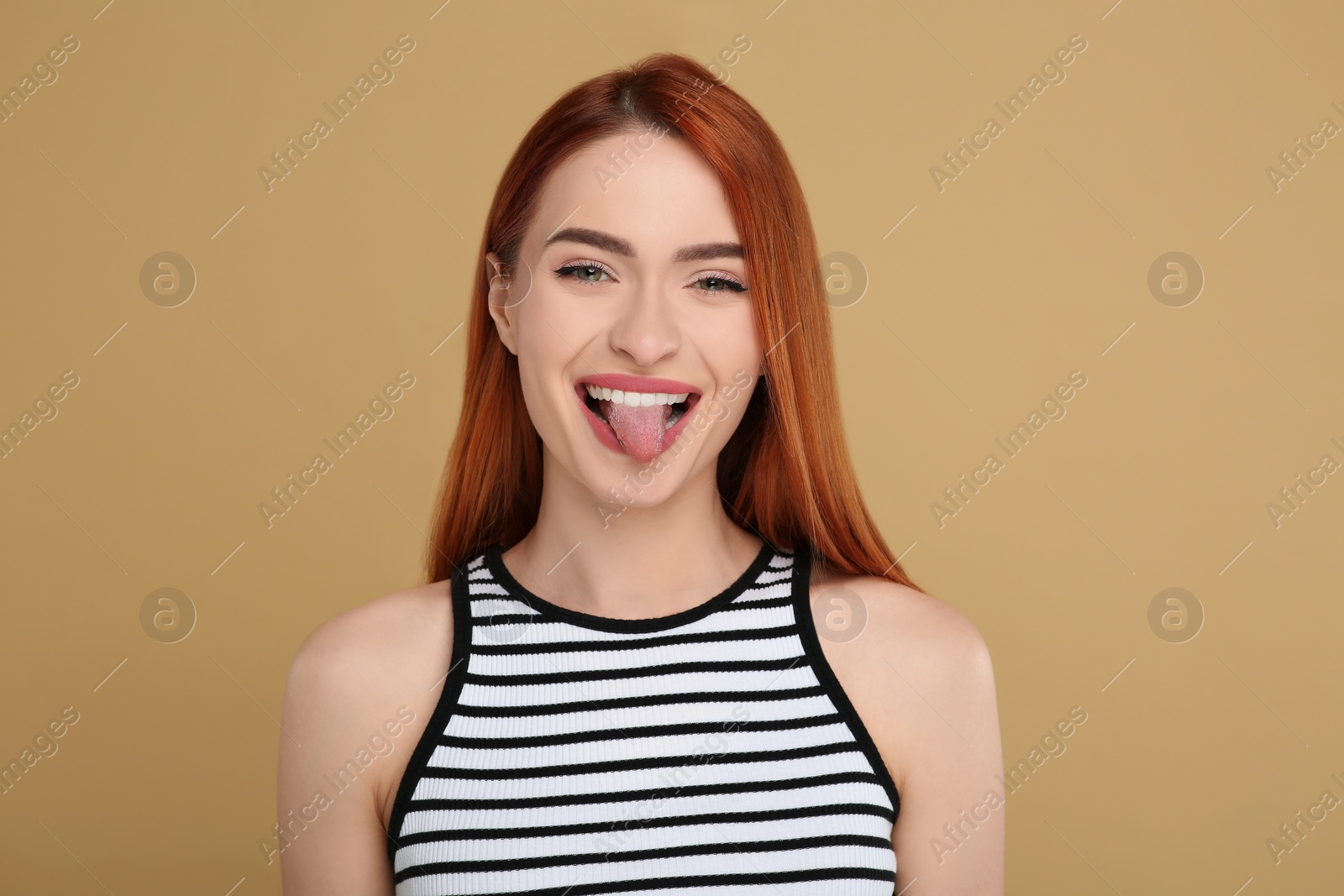 Photo of Happy woman showing her tongue on beige background