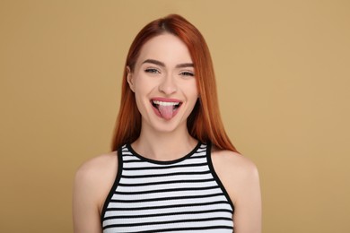 Happy woman showing her tongue on beige background